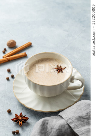 Traditional Indian masala chai tea with milk and spices in a white cup on a light background Traditional Indian masala chai tea with milk and spices in a white cup on a light background 132200809