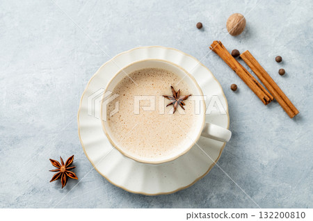 Traditional Indian masala chai tea with milk and spices in a white cup on a light background Traditional Indian masala chai tea with milk and spices in a white cup on a light background 132200810