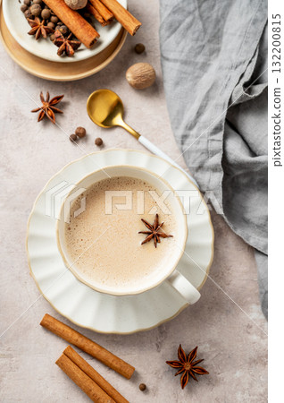 Traditional Indian masala chai tea with milk and spices in a white cup on a light background 132200815