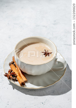 Traditional Indian masala chai tea with milk and spices in a white cup on a light background Traditional Indian masala chai tea with milk and spices in a white cup on a light background 132200820