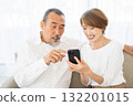 一對老年夫婦在沙發上放鬆並使用智慧型手機 132201015