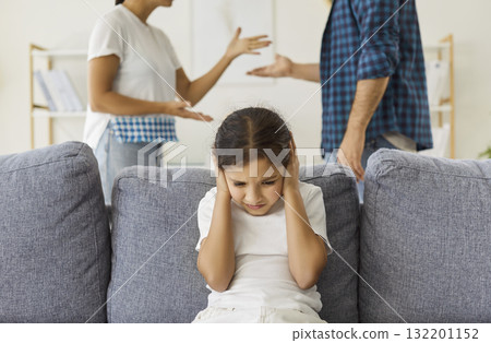 Sad child holding hands to ears to cover and ignore parents quarrel at home 132201152