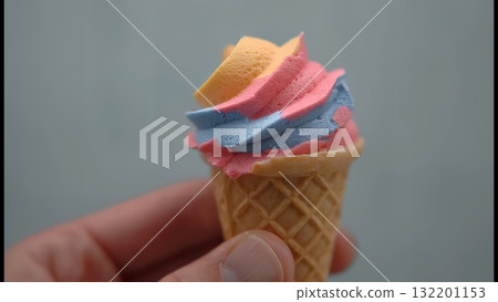 手指間夾著的彩色迷你軟冰淇淋的特寫 132201153
