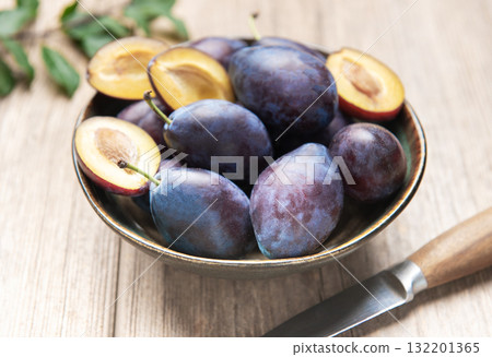 Fresh ripe plums in bowl on wood surface 132201365