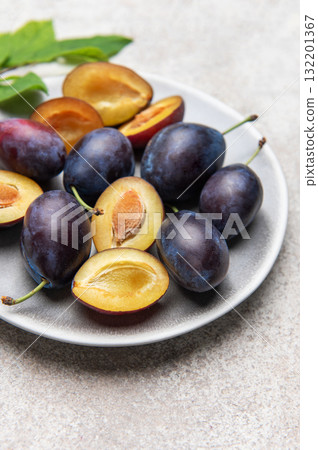 Fresh plums on plate showing halved fruit composition Fresh plums on plate showing halved fruit composition 132201367