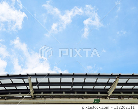 Blue Sky and Clouds Over a Modern Metal and Glass Structure. 132202111