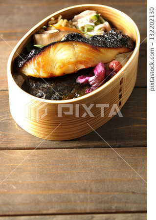 A bento lunch box with seaweed and grilled silver cod in a bento box. A bento lunch box with seaweed and grilled silver cod in a bento box. 132202130