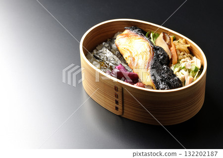 一張便當盒,裡面有海藻和西京風味醬汁烤銀鱈魚,以黑色背景拍攝 一張便當盒,裡面有海藻和西京風味醬汁烤銀鱈魚,以黑色背景拍攝 132202187