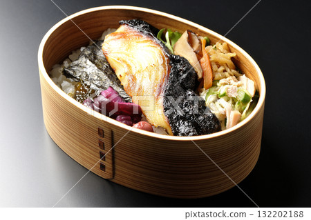 一張便當盒,裡面有海藻和西京風味醬汁烤銀鱈魚,以黑色背景拍攝 一張便當盒,裡面有海藻和西京風味醬汁烤銀鱈魚,以黑色背景拍攝 132202188