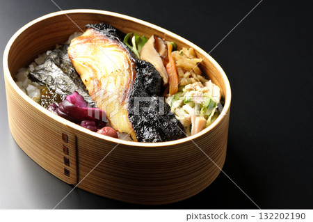 A bento lunch box with seaweed and grilled silver cod in a saikyo style sauce, photographed against a black background A bento lunch box with seaweed and grilled silver cod in a saikyo style sauce, photographed against a black background 132202190