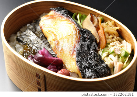 一張便當盒,裡面有海藻和西京風味醬汁烤銀鱈魚,以黑色背景拍攝 一張便當盒,裡面有海藻和西京風味醬汁烤銀鱈魚,以黑色背景拍攝 132202191