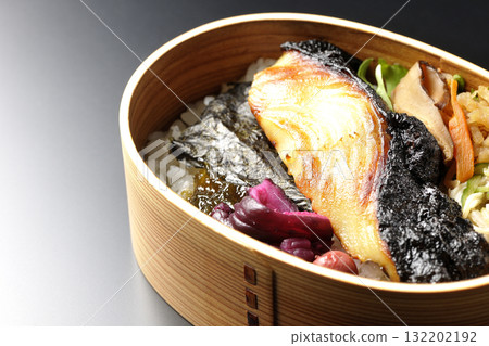 A bento lunch box with seaweed and grilled silver cod in a saikyo style sauce, photographed against a black background A bento lunch box with seaweed and grilled silver cod in a saikyo style sauce, photographed against a black background 132202192