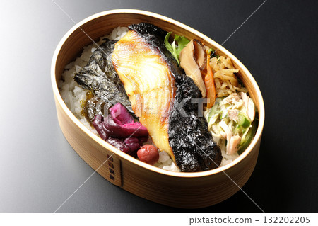 A bento lunch box with seaweed and grilled silver cod in a saikyo style sauce, photographed against a black background A bento lunch box with seaweed and grilled silver cod in a saikyo style sauce, photographed against a black background 132202205
