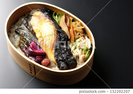 A bento lunch box with seaweed and grilled silver cod in a saikyo style sauce, photographed against a black background A bento lunch box with seaweed and grilled silver cod in a saikyo style sauce, photographed against a black background 132202207