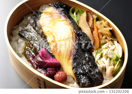 A bento lunch box with seaweed and grilled silver cod in a saikyo style sauce, photographed against a black background A bento lunch box with seaweed and grilled silver cod in a saikyo style sauce, photographed against a black background 132202208