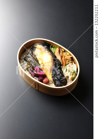 A bento lunch box with seaweed and grilled silver cod in a saikyo style sauce, photographed against a black background 132202211
