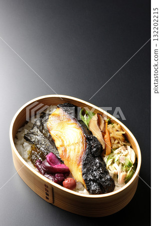 A bento lunch box with seaweed and grilled silver cod in a saikyo style sauce, photographed against a black background A bento lunch box with seaweed and grilled silver cod in a saikyo style sauce, photographed against a black background 132202215