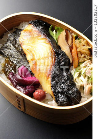 A bento lunch box with seaweed and grilled silver cod in a saikyo style sauce, photographed against a black background A bento lunch box with seaweed and grilled silver cod in a saikyo style sauce, photographed against a black background 132202217