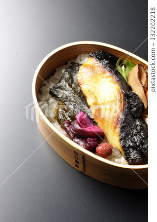 A bento lunch box with seaweed and grilled silver cod in a saikyo style sauce, photographed against a black background A bento lunch box with seaweed and grilled silver cod in a saikyo style sauce, photographed against a black background 132202218