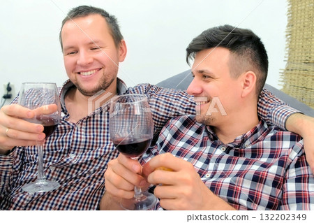 Men gay relax flirting each other and drinking a red wine hugging. Men gay relax flirting each other and drinking a red wine hugging. 132202349
