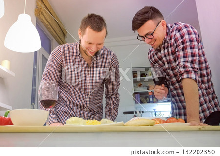 Couple of men gay flirts each other cooking a pizza together and drinking a wine. Couple of men gay flirts each other cooking a pizza together and drinking a wine. 132202350