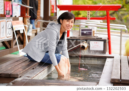 A woman bathing in a foot bath at the Oyasukyo General Information Center 132202503