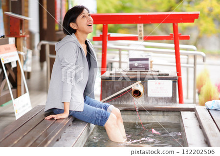 A woman bathing in a foot bath at the Oyasukyo General Information Center 132202506