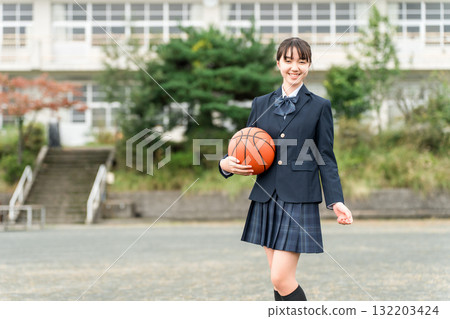 穿著校服的高中、國中和小學女生站在校園裡，手裡拿著籃球 132203424