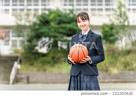 穿著校服的高中、國中和小學女生站在校園裡，手裡拿著籃球 132203426