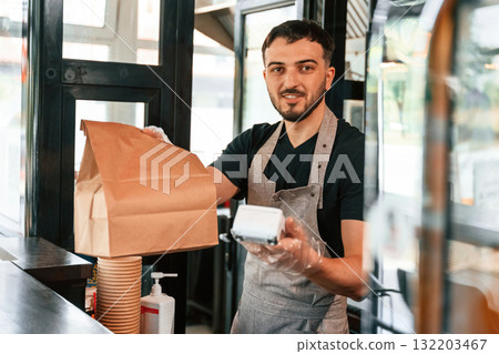 Payment by using terminal, order is ready. Man is serving delicious street food 132203467