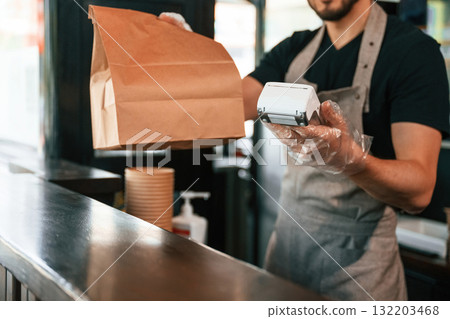 Payment by using terminal, order is ready. Man is serving delicious street food 132203468