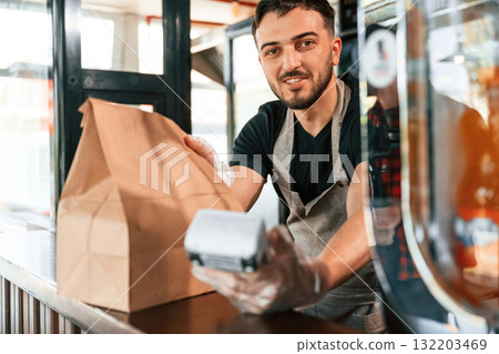 Payment by using terminal, order is ready. Man is serving delicious street food Payment by using terminal, order is ready. Man is serving delicious street food 132203469