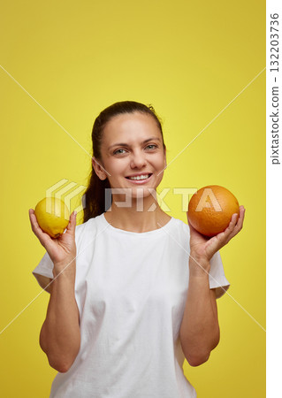 happy woman holding fresh lemon and grapefruit on yellow studio background, healthy eating happy woman holding fresh lemon and grapefruit on yellow studio background, healthy eating 132203736