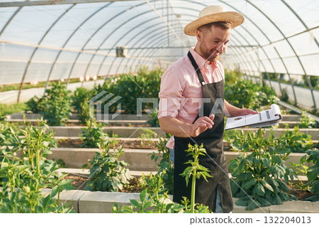 Reading the data. Man in greenhouse is working with plants Reading the data. Man in greenhouse is working with plants 132204013