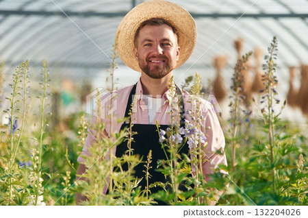 Cheerful facial expression. Man in greenhouse is working with plants 132204026