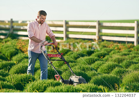 Using lawn mower. Adult farmer is outdoors 132204037