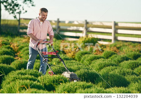 Using lawn mower. Adult farmer is outdoors Using lawn mower. Adult farmer is outdoors 132204039