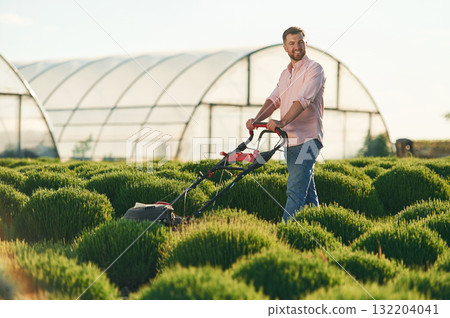 With lawn mower. Adult farmer is outdoors 132204041