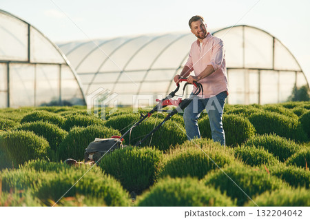 With lawn mower. Adult farmer is outdoors 132204042