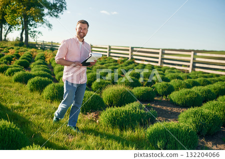 Documents in the notepad in hands. Adult farmer is outdoors 132204066