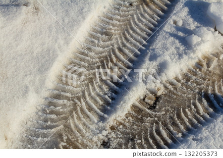 Tire tracks visible in fresh snow on a winter day near a forested area in a rural location 132205373