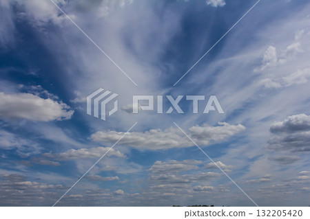 Vast blue sky filled with wispy clouds creating a serene and peaceful atmosphere in a rural landscape during midday 132205420