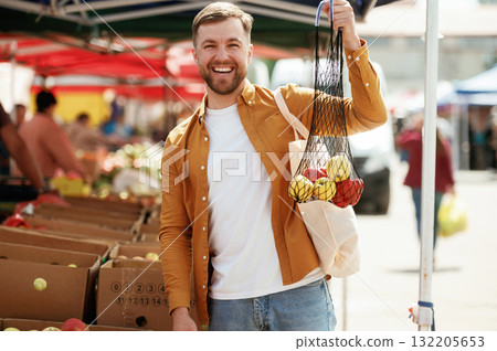 Pepper and apples, smiling. Handsome man is on the street market or bazaar 132205653