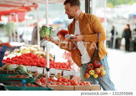 Paper shopping list. Handsome man is on the street market or bazaar 132205666