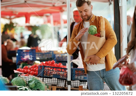 Shopping bag full of products. Handsome man is on the street market or bazaar Shopping bag full of products. Handsome man is on the street market or bazaar 132205672