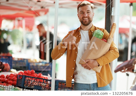 Collection of products in paper bag. Handsome man is on the street market or bazaar Collection of products in paper bag. Handsome man is on the street market or bazaar 132205676