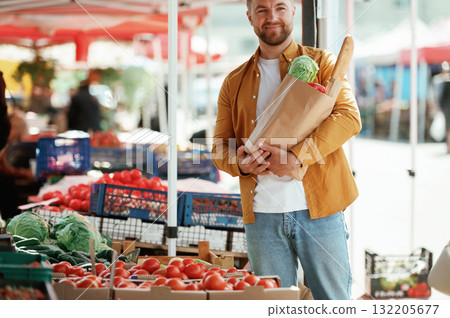 Collection of products in paper bag. Handsome man is on the street market or bazaar Collection of products in paper bag. Handsome man is on the street market or bazaar 132205677