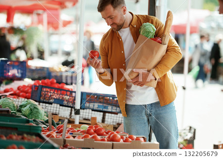 Collection of products in paper bag. Handsome man is on the street market or bazaar 132205679