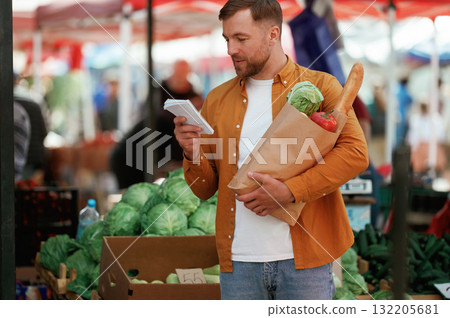 Paper shopping list. Handsome man is on the street market or bazaar Paper shopping list. Handsome man is on the street market or bazaar 132205681