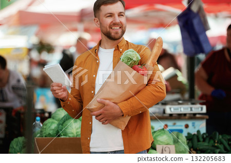 Paper shopping list. Handsome man is on the street market or bazaar Paper shopping list. Handsome man is on the street market or bazaar 132205683
